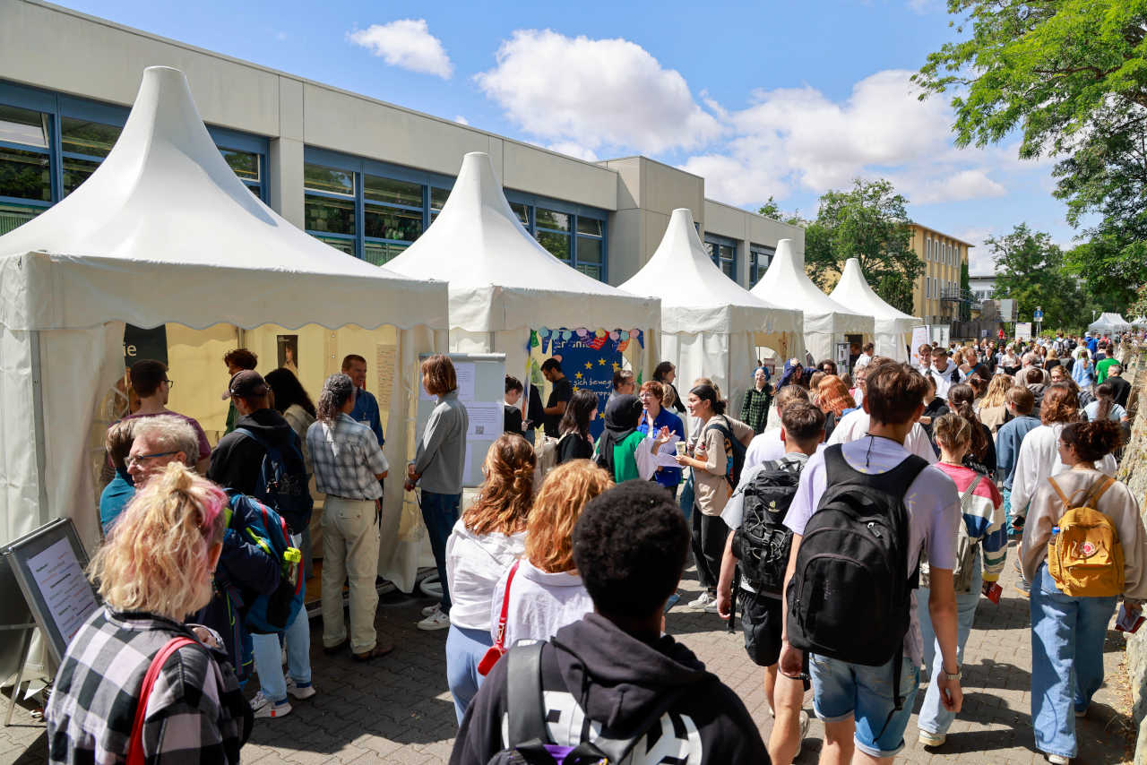 Besucherinnen und Besucher beim Tag der offenen Uni. Im Hintergrund Pavillons und das Rewi-Gebäude.